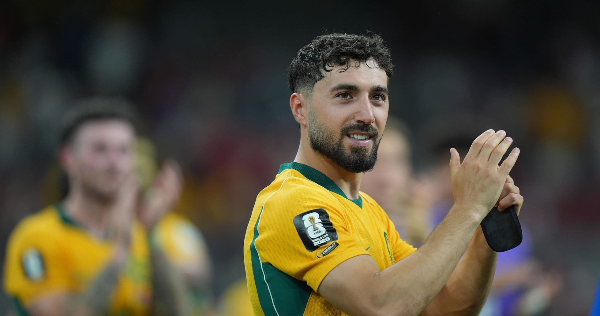 Player in yellow jersey applauding fans after match