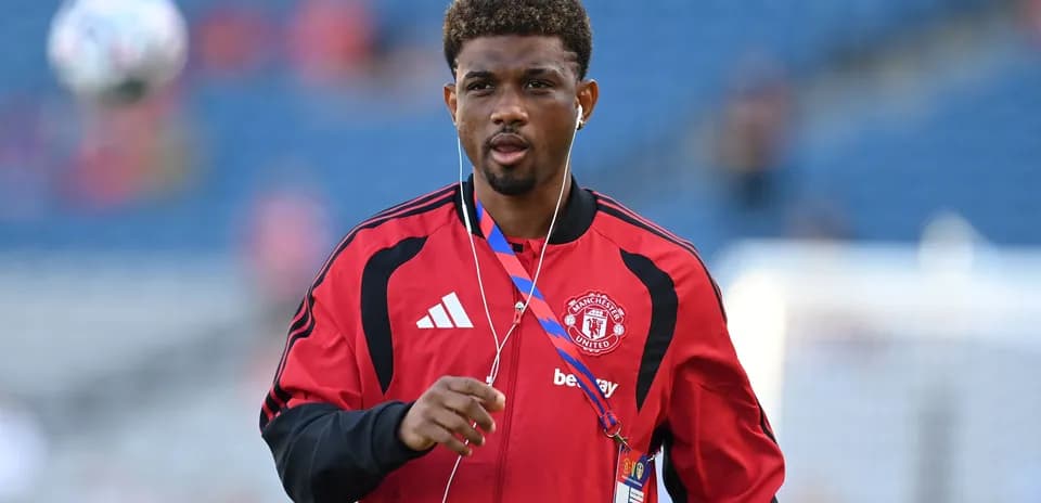 Player walking on pitch wearing Manchester United tracksuit