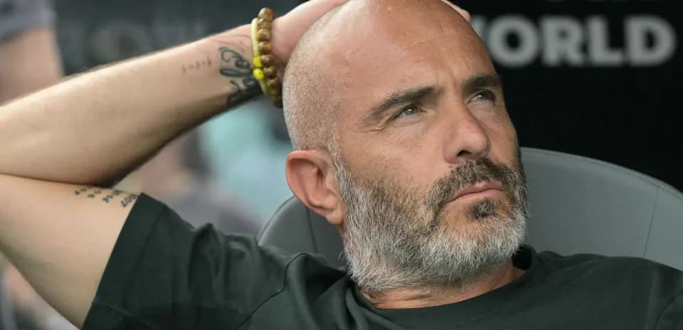Coach seated, observing match from sidelines