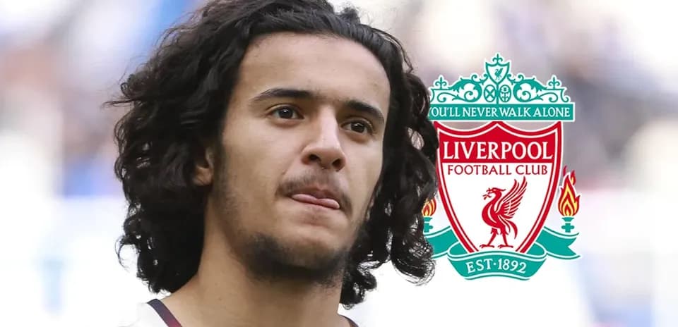 Player with long hair in front of Liverpool FC logo