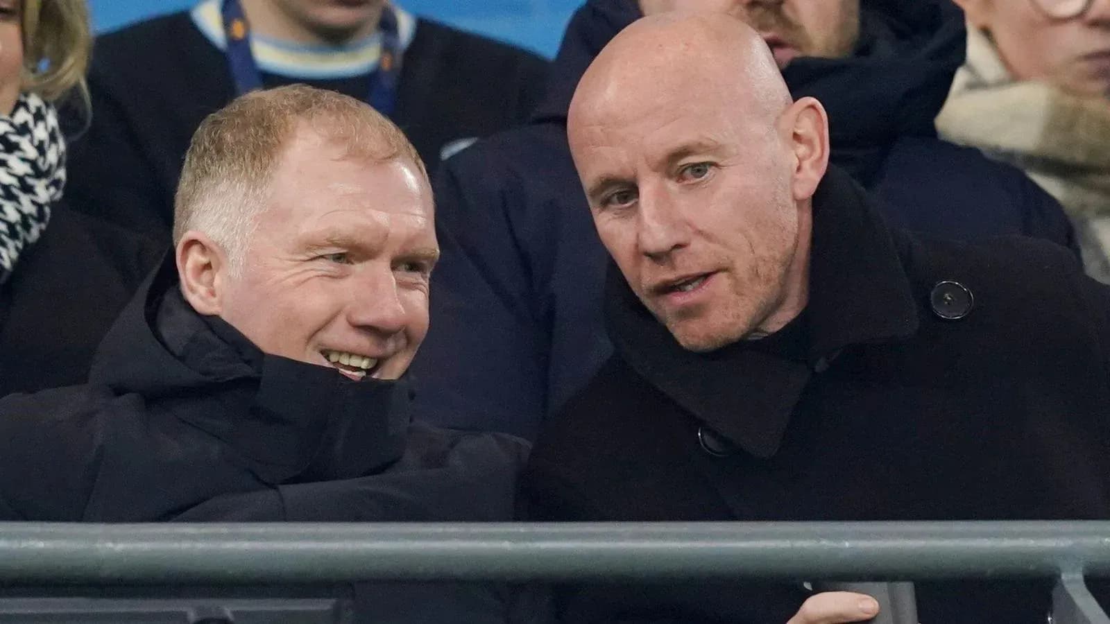 Two men conversing in stadium seats during match
