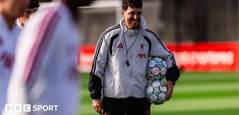 Liverpool staff member carrying footballs during training