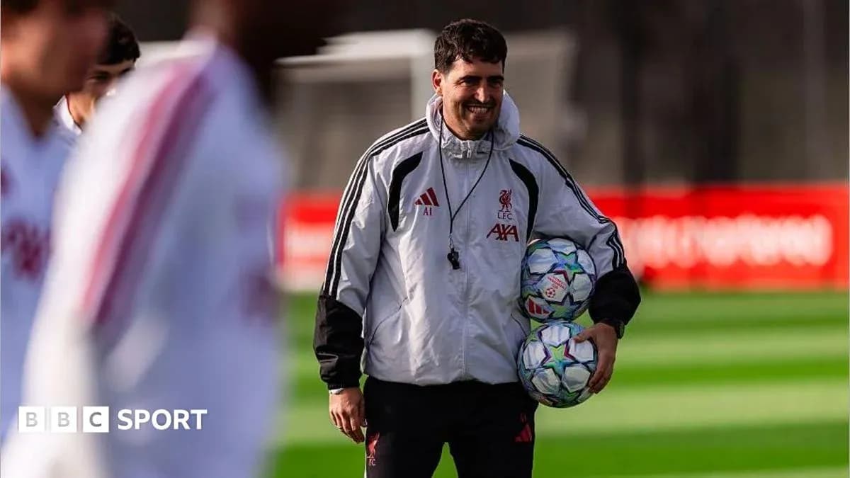 Liverpool staff member carrying footballs during training