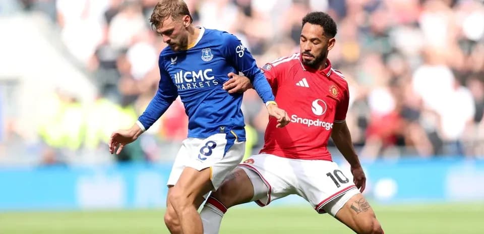 Everton player tackling Manchester United player during match