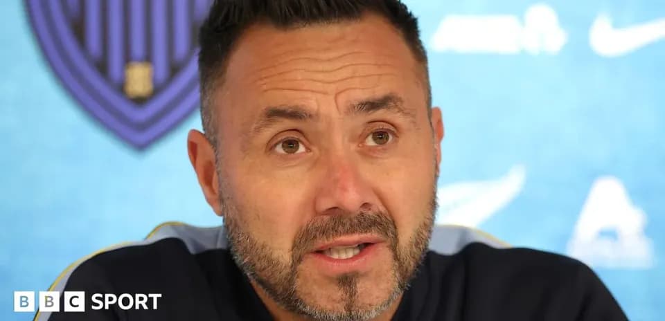 Manager speaking at press conference with blue backdrop