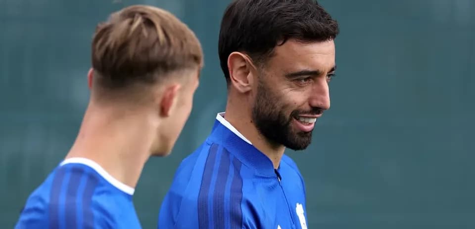 Two football players in blue training kits talking