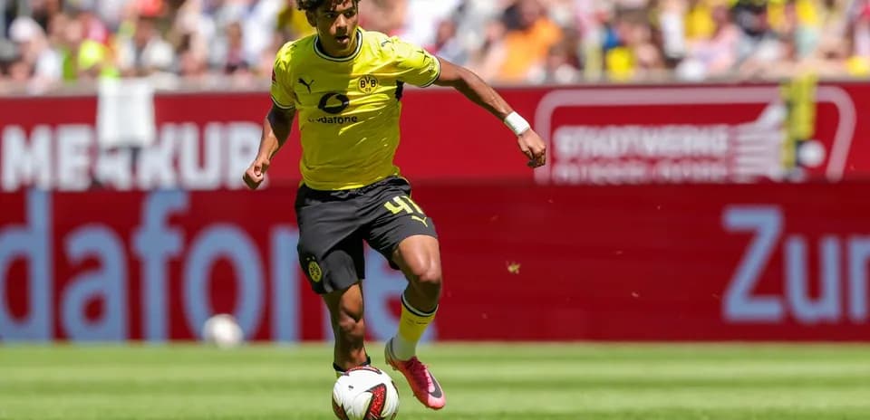 Player in yellow kit dribbling the ball on pitch