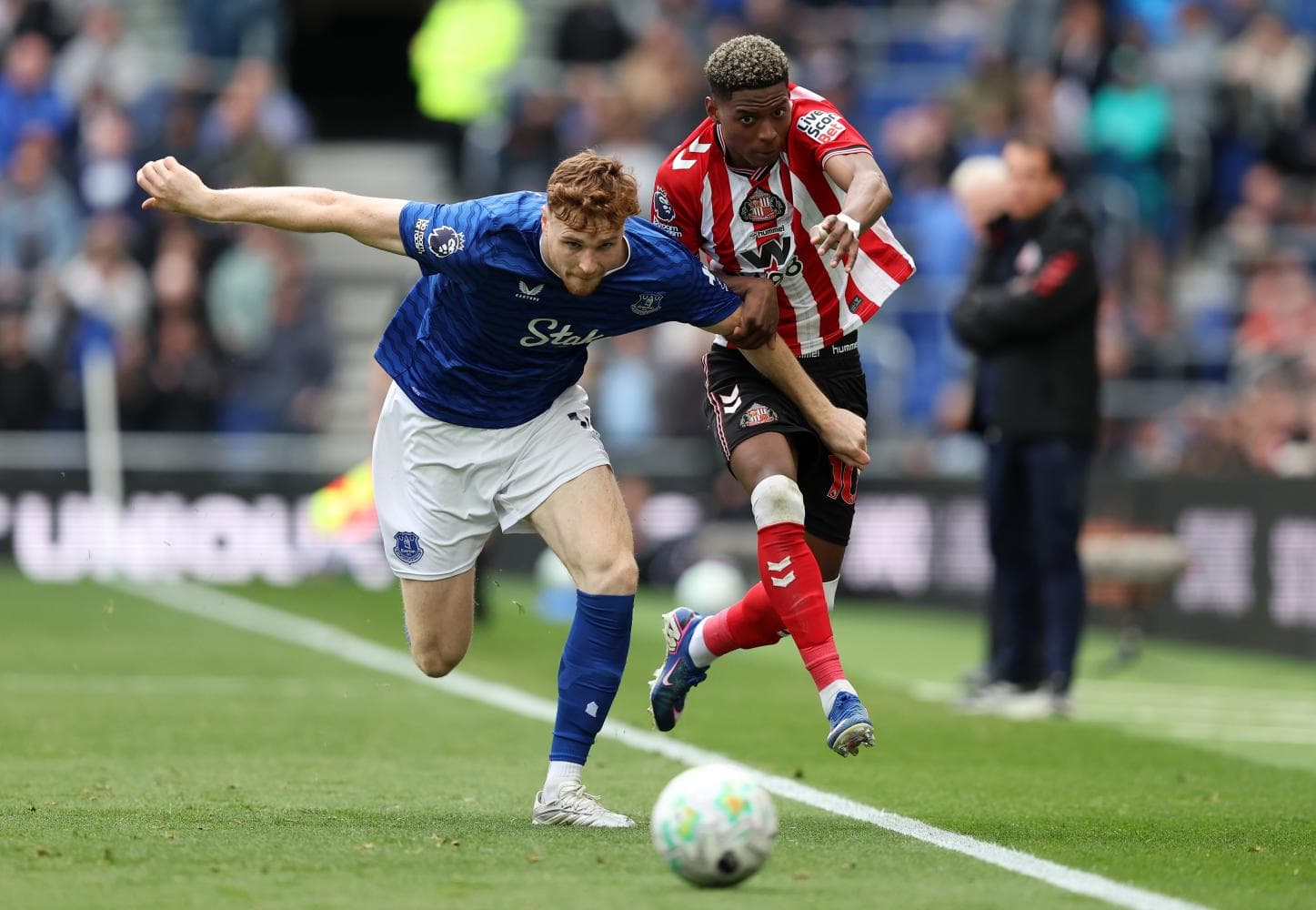 Everton player challenging Sunderland opponent for the ball