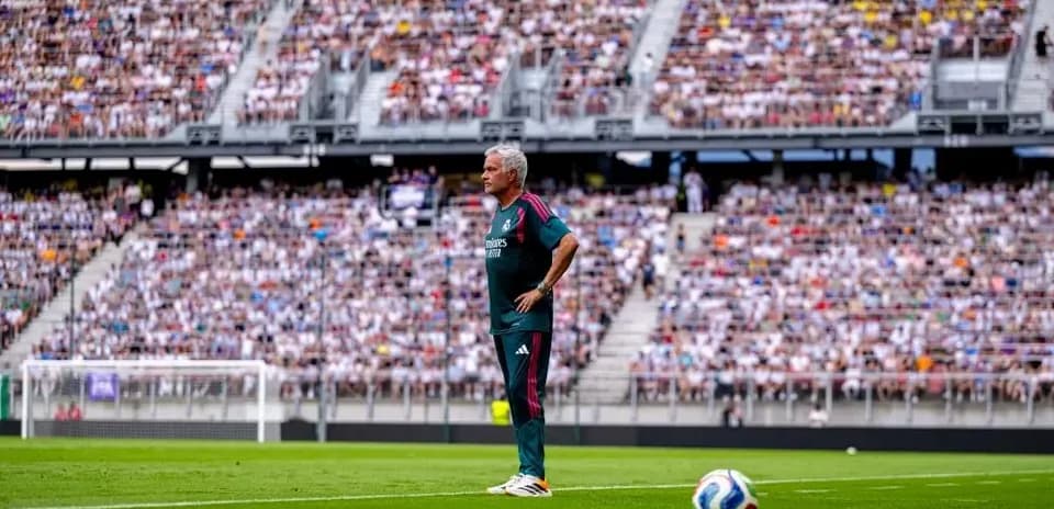 Coach observing the game with a packed stadium