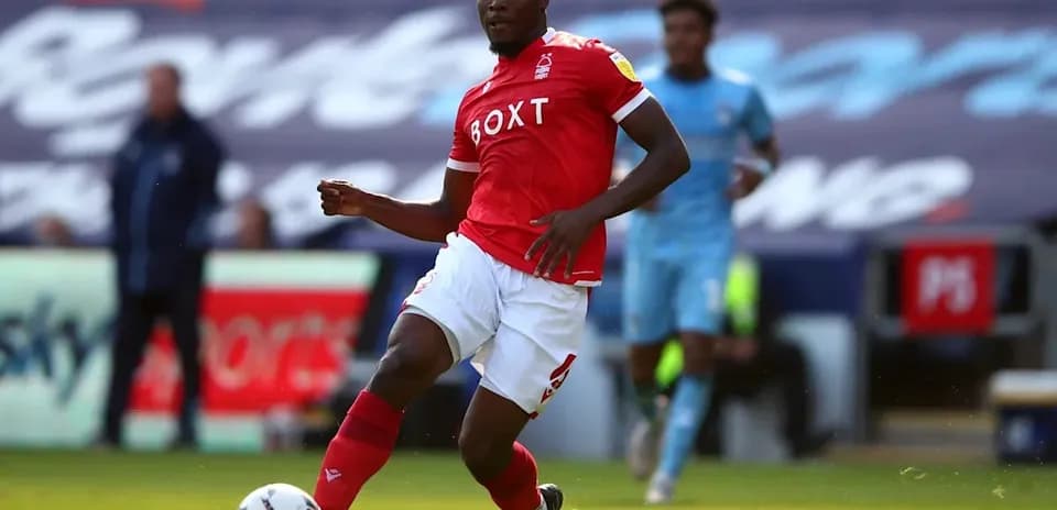 Player in red jersey dribbling the ball on field