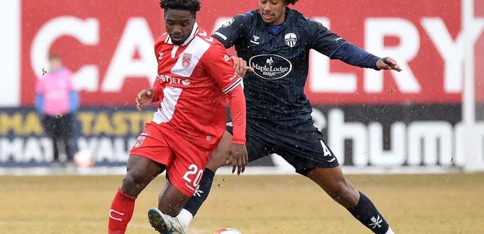 Player tackling during Atlético Ottawa vs Cavalry FC match