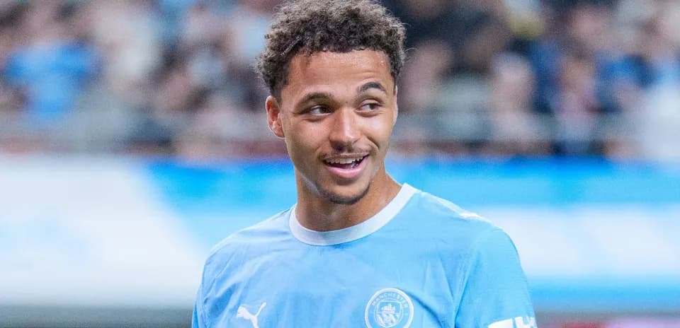 Player in Manchester City kit smiling on field