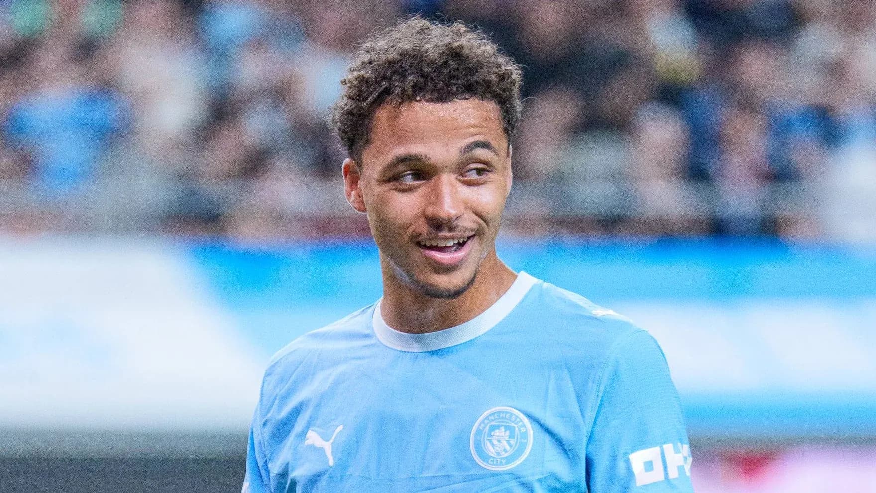 Player in Manchester City kit smiling on field