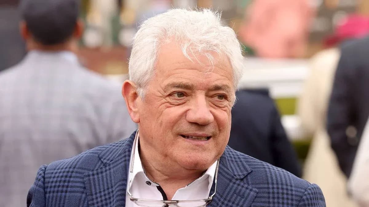 Man with white hair wearing a blue checked blazer