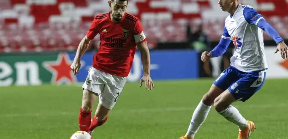 Benfica player dribbling past Lech Poznan opponent