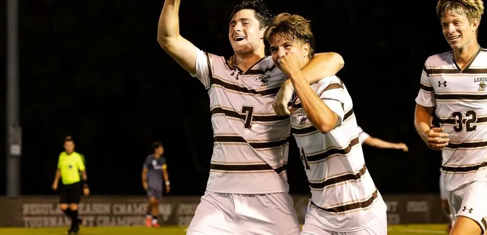 Two soccer players celebrating a goal on field
