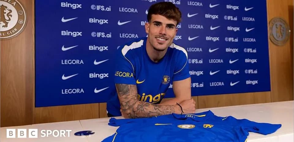 Player posing with Chelsea jersey at signing event
