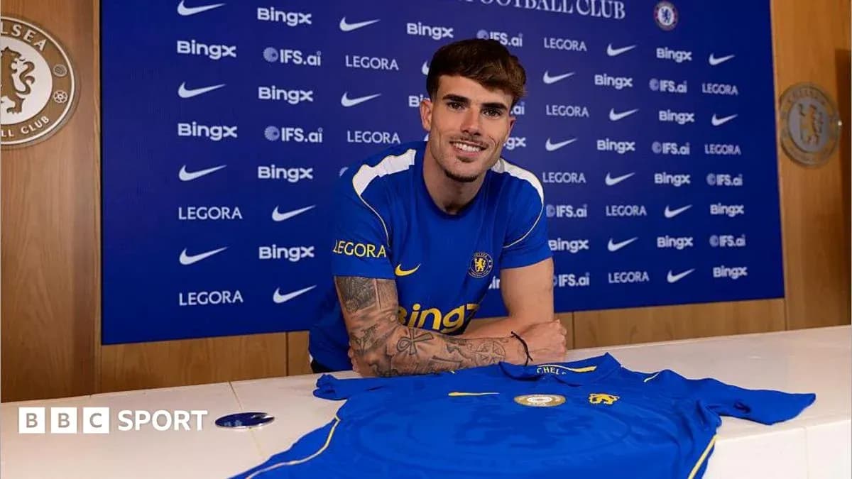 Player posing with Chelsea jersey at signing event