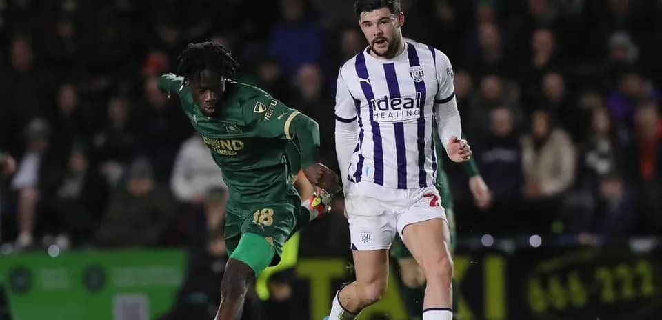 Player in green chasing player in white during match