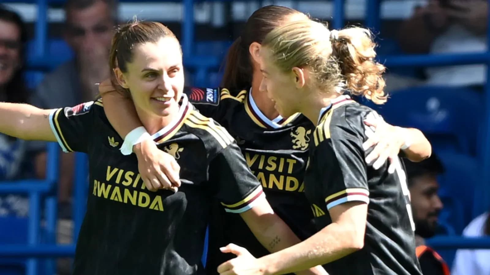 Three players celebrating a goal in team jerseys