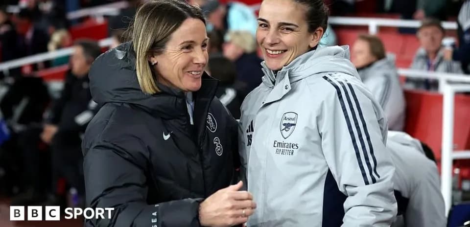 Two coaches smiling and conversing on sidelines