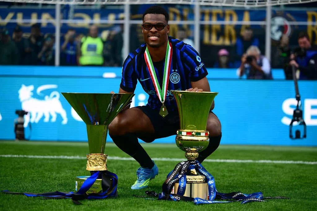 Player celebrating with two trophies on the field Player celebrating with two trophies on the field
