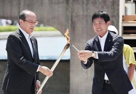 Two officials passing a ceremonial torch outdoors