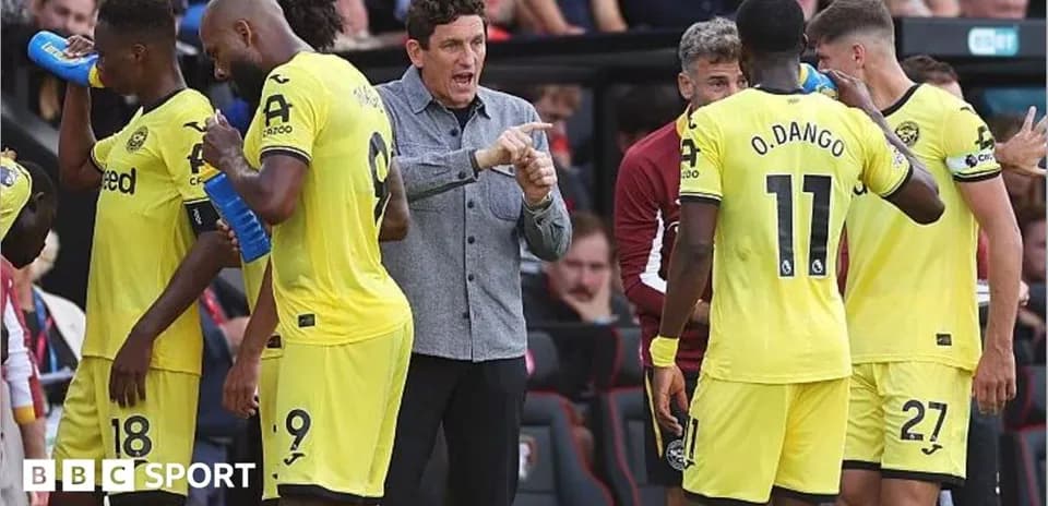 Brentford players receiving instructions from coach during match