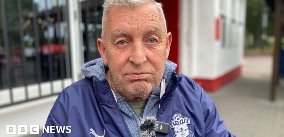 Man wearing Southampton FC jacket sitting outdoors