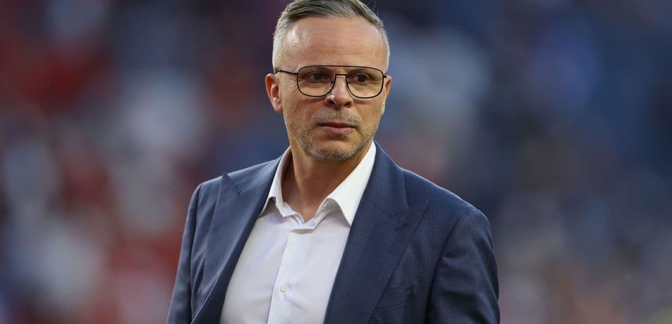Man in suit with glasses on stadium field