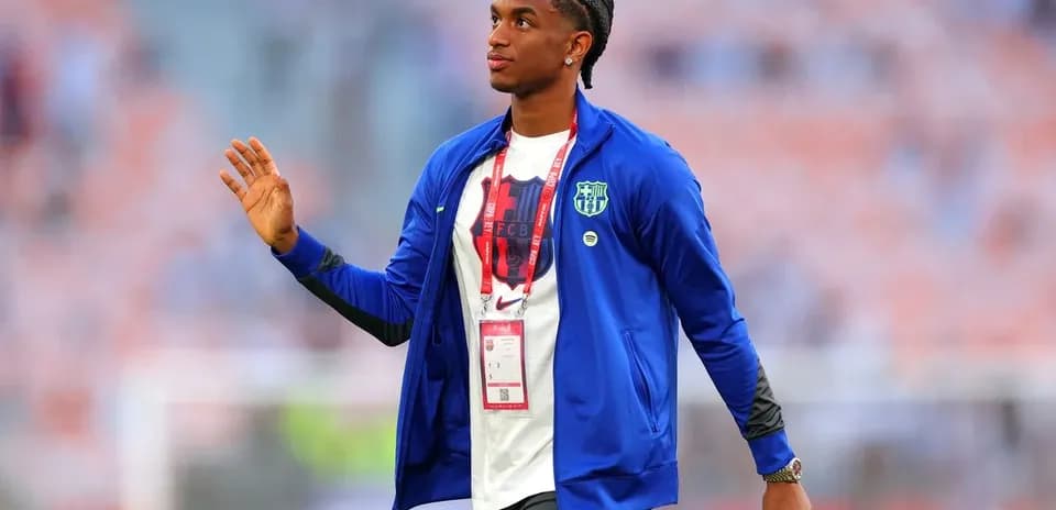 Player walking on field with team jacket and ID badge