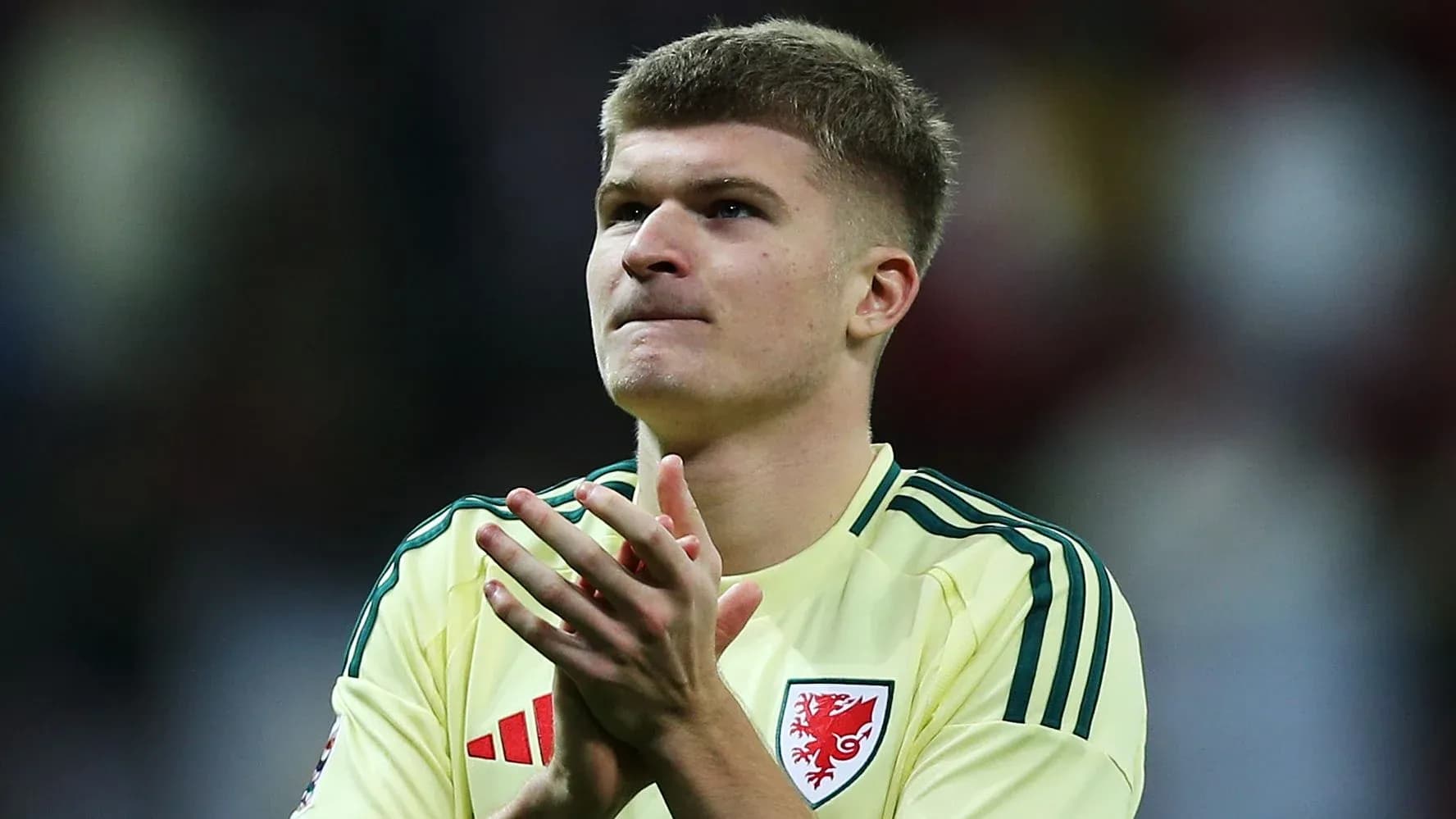 Player in yellow jersey applauding fans after match