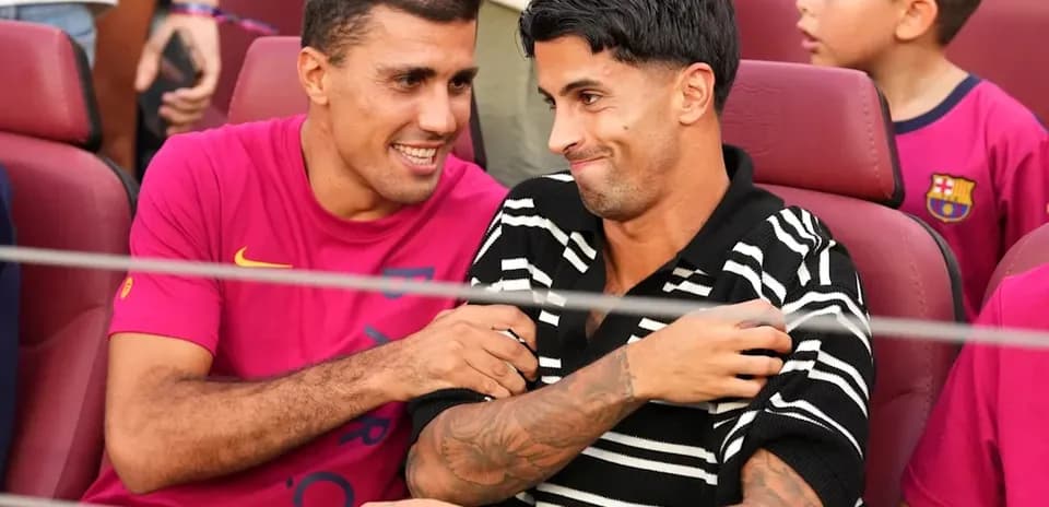 Two football players seated, smiling and interacting