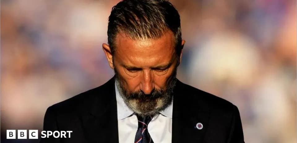 Coach with head down during press event