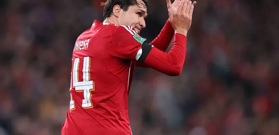 Player applauding fans while wearing red kit