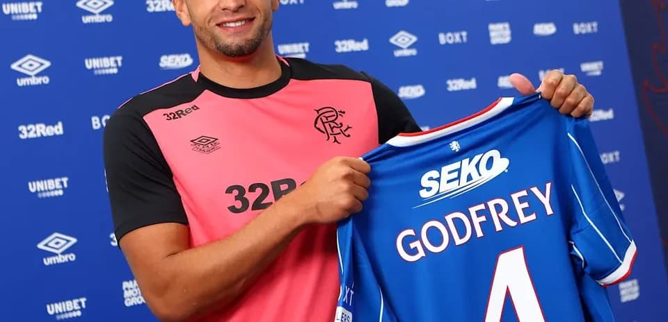 Player holding new jersey at press conference