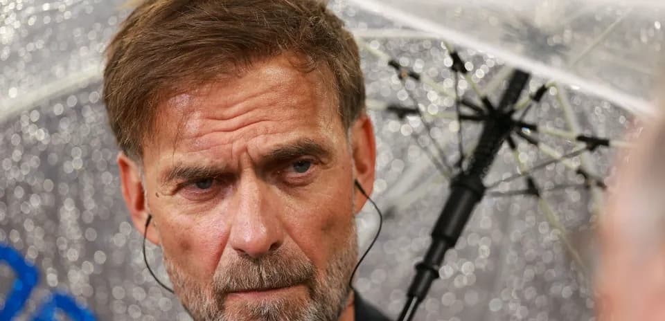 Manager under umbrella during rainy press conference