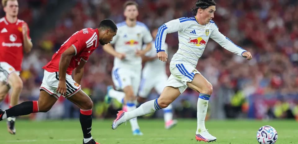 Player in white sprinting past defender in red jersey