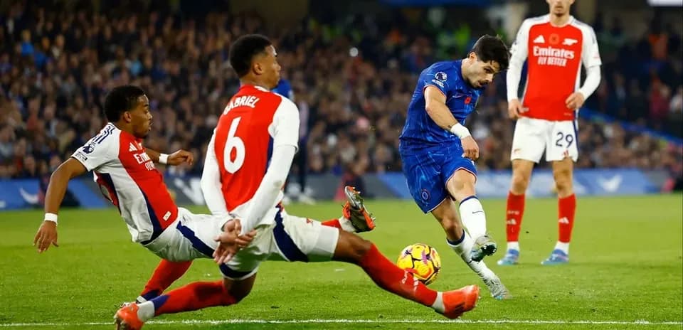 Chelsea player shooting at goal with Arsenal defenders nearby
