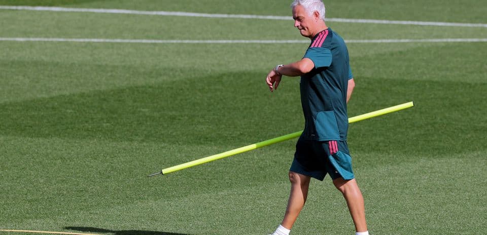 Coach walking on pitch holding training equipment