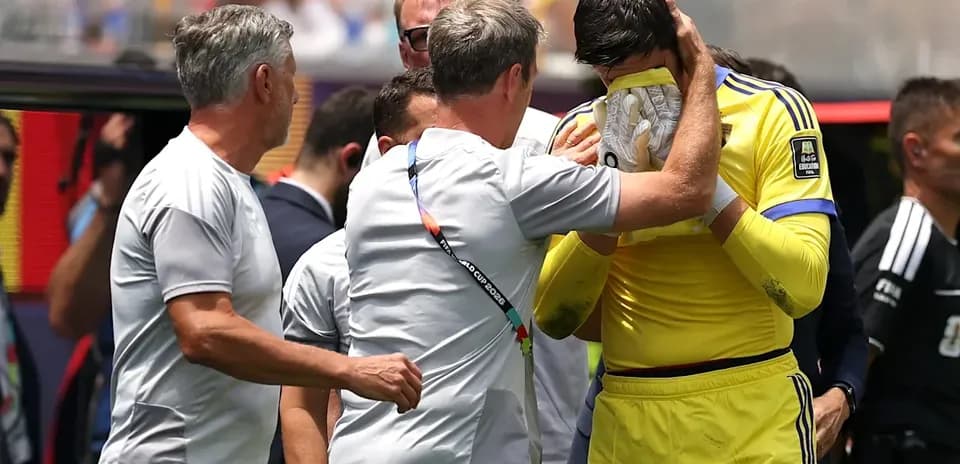 Goalkeeper receiving support from coaching staff on sidelines