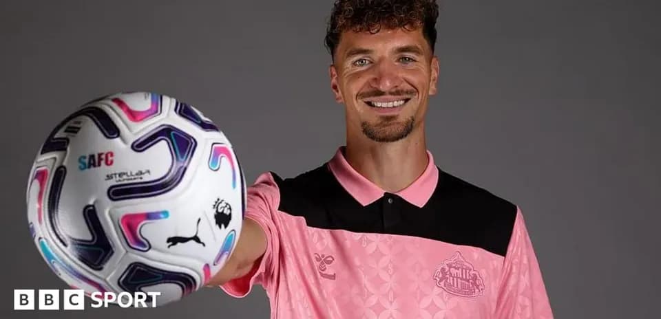 Player holding a football in team jersey