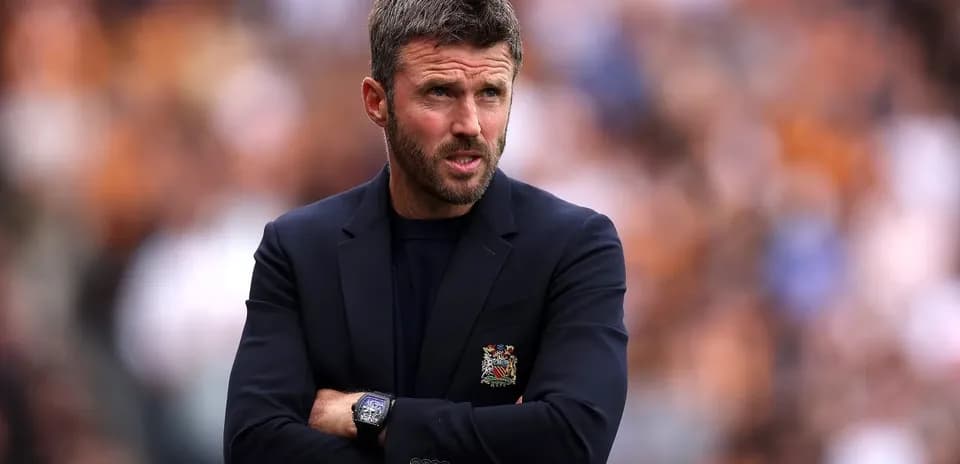 Coach standing with arms crossed during match