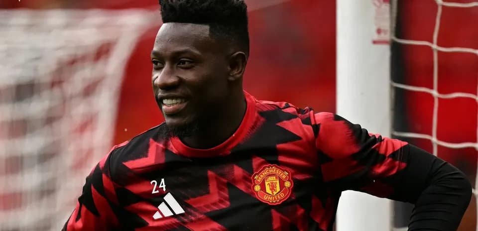 Goalkeeper in Manchester United kit smiling during warm-up