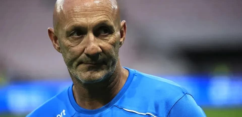 Coach in blue training kit on the pitch