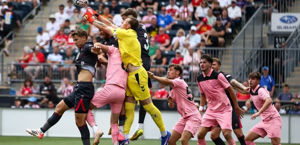 Goalkeeper catching the ball amid player crowding