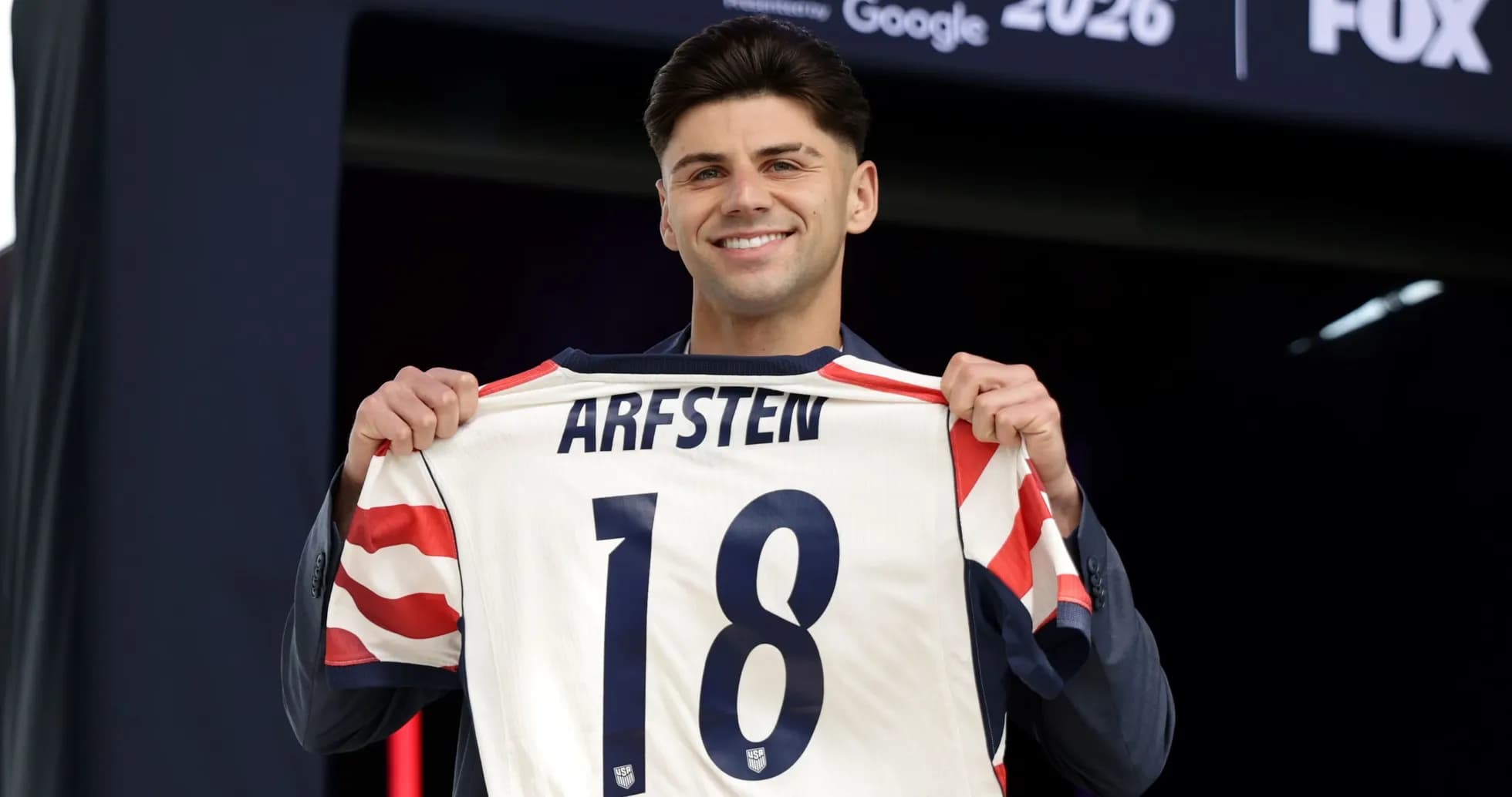 Player holding jersey with name 'ARFSTEN' and number 18