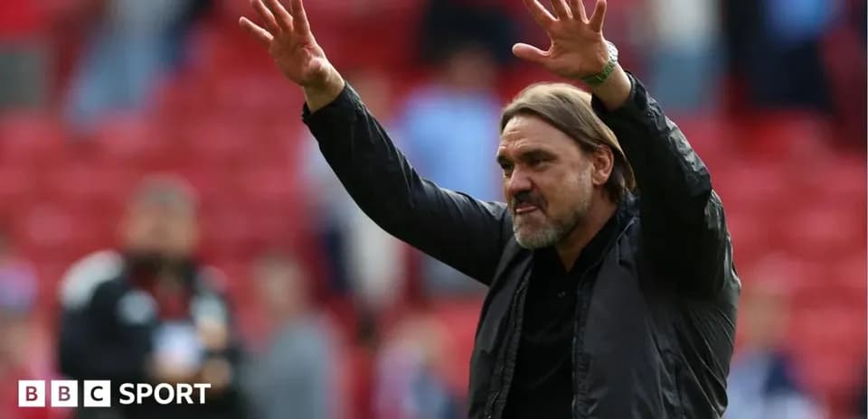 Manager gesturing to fans in stadium stands