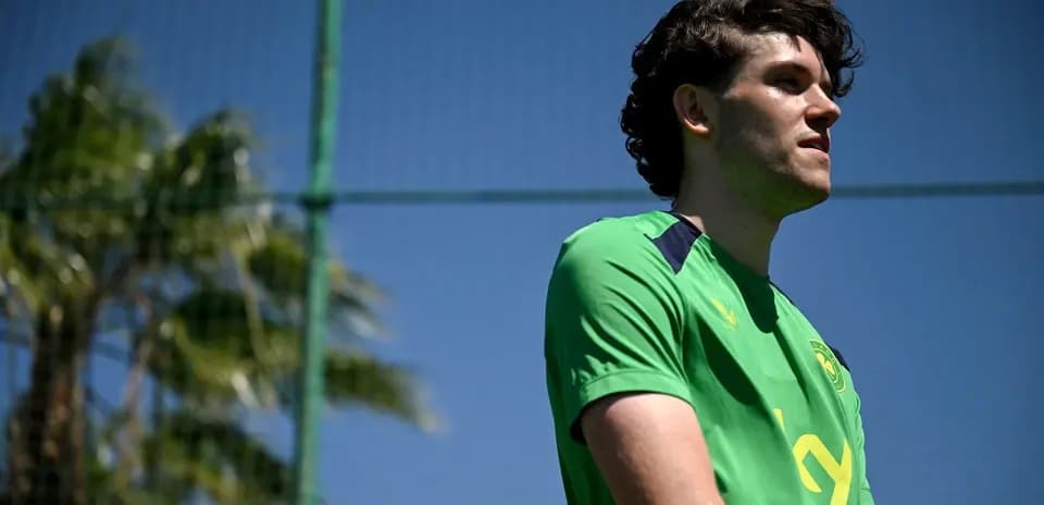 Player in green kit standing near training field