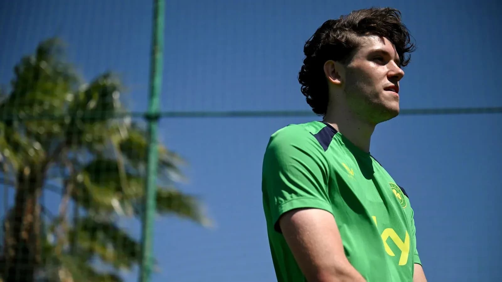 Player in green kit standing near training field